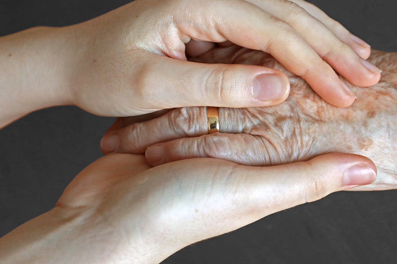 Foto der Hand einer alten Frau, die von den Händen einer jungen Frau gehalten wird